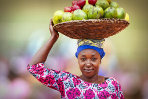 Rwandan woman carrying basket full of fruits